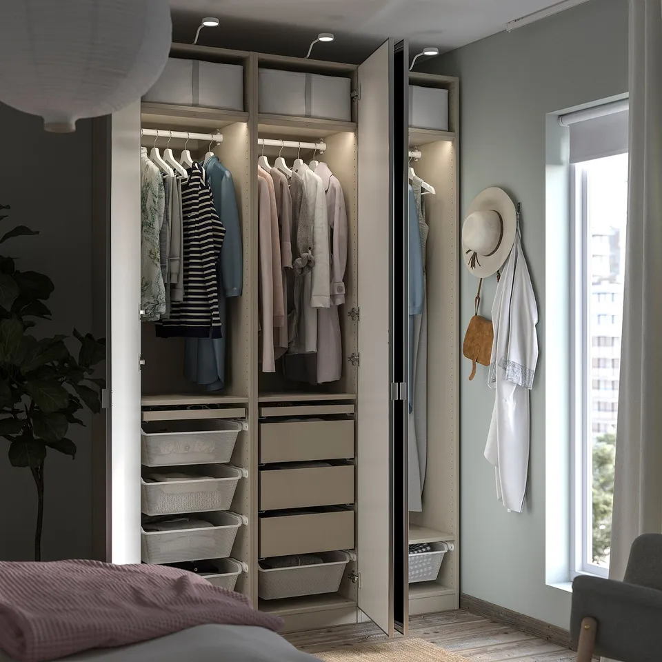 Modern bedroom closet with open doors showing clothes, baskets, and accessories. Neutral colours with lit shelves.