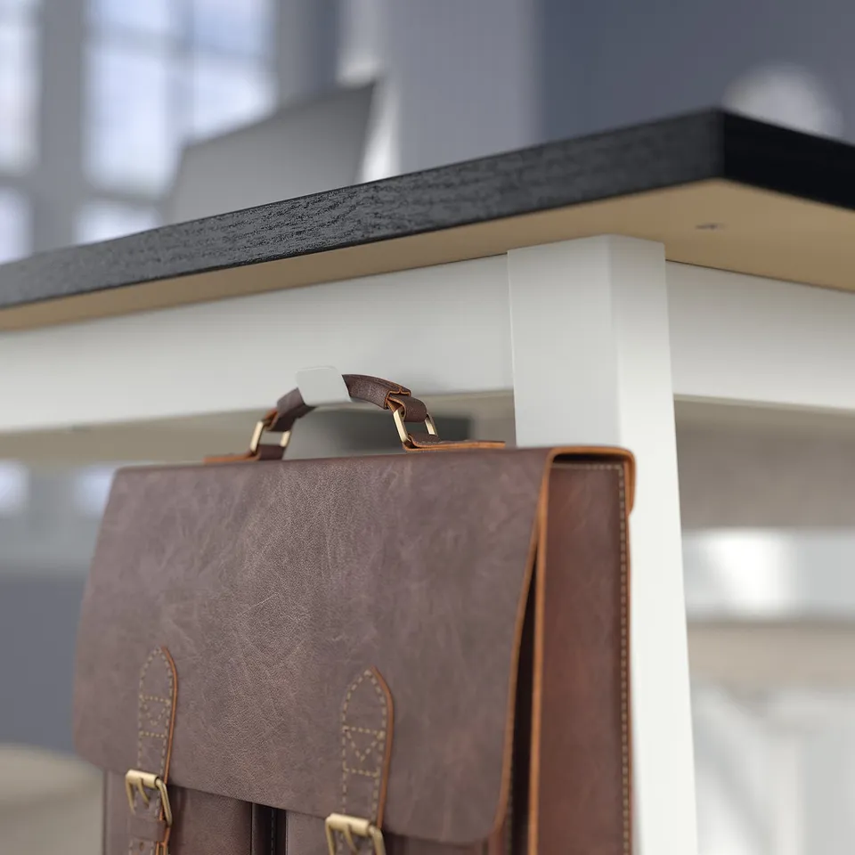 Leather bag hangs on metal shelf, showing its strap and buckle, suggesting use for carrying.