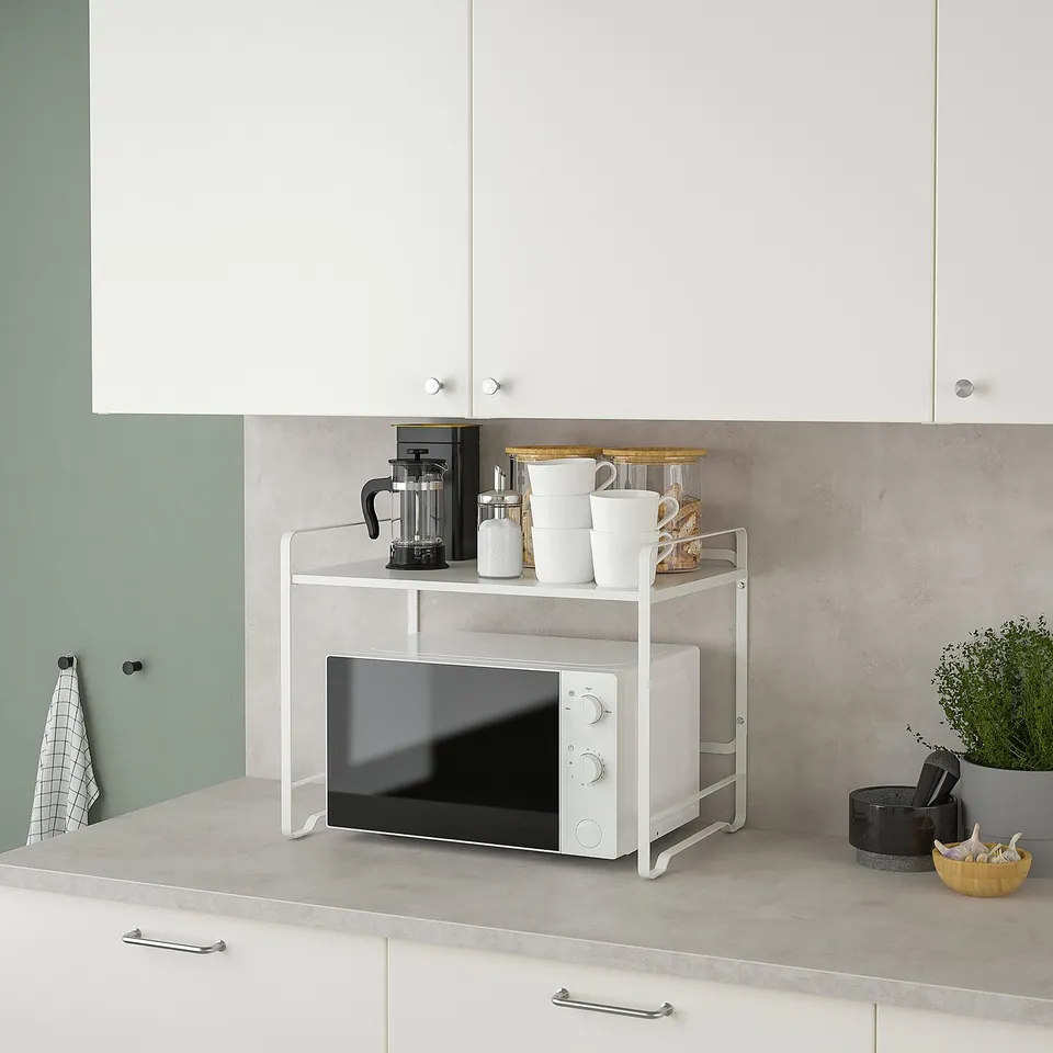 Kitchen counter with AVSTEG double shelf unit. Microwave and coffee maker are stored neatly, saving space and keeping the area tidy.