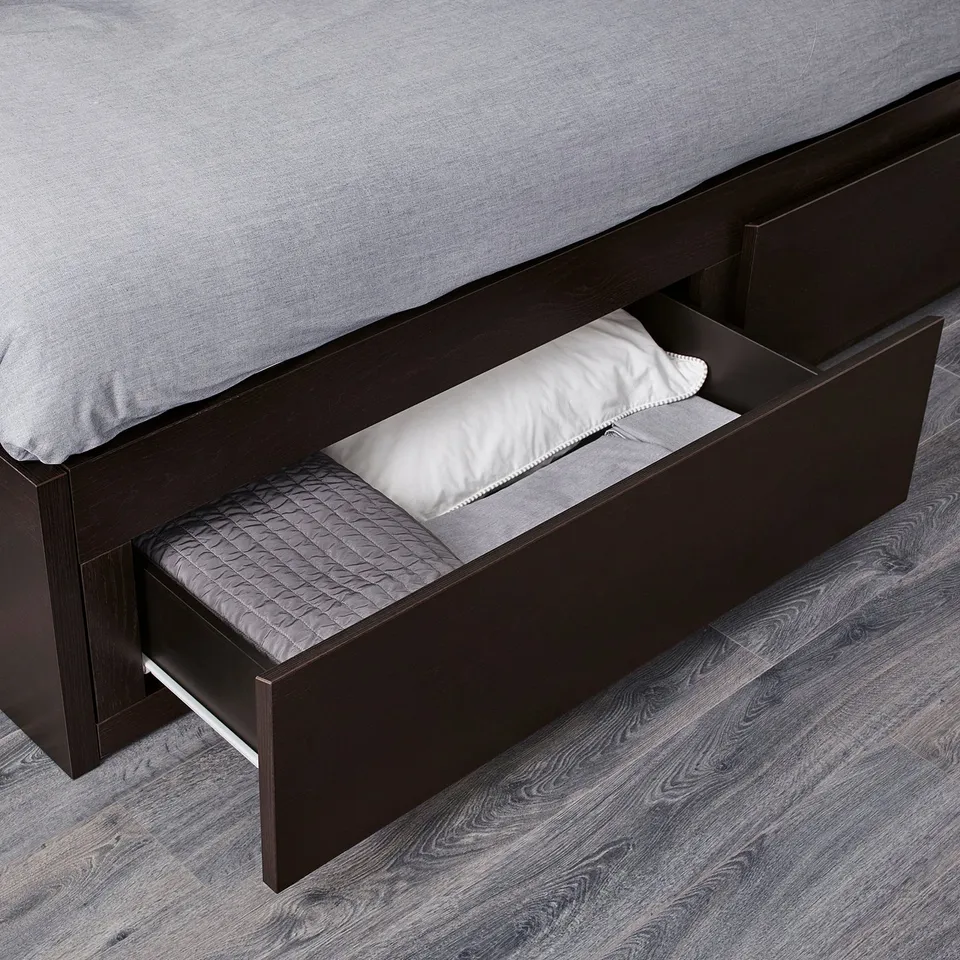 Bed with open storage drawer showing pillow and blanket, demonstrating storage functionality.