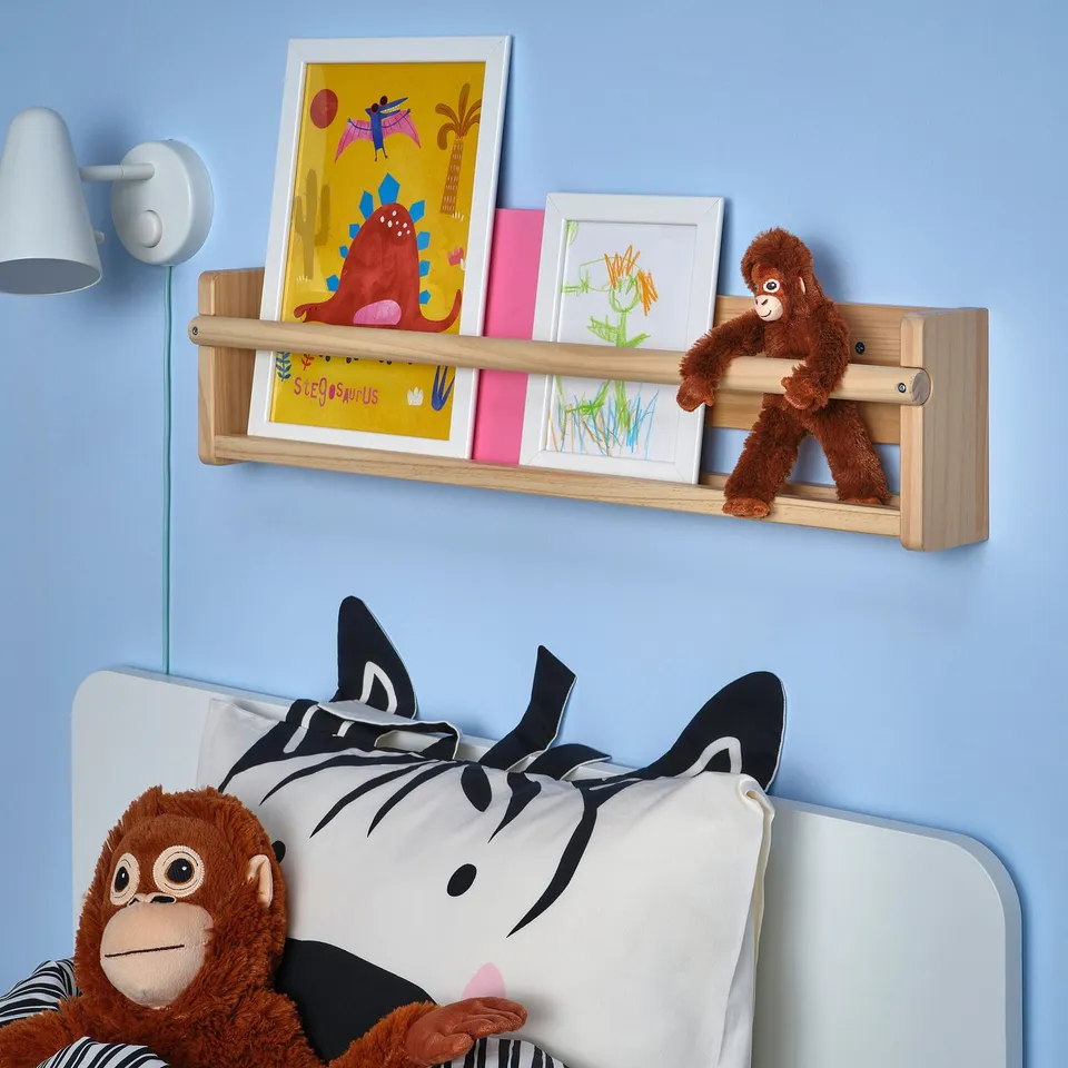 Kids room with blue walls, zebra pillow bed, orange monkey toy, shelf with drawings, lamp, DJUNGELSKOG decor.