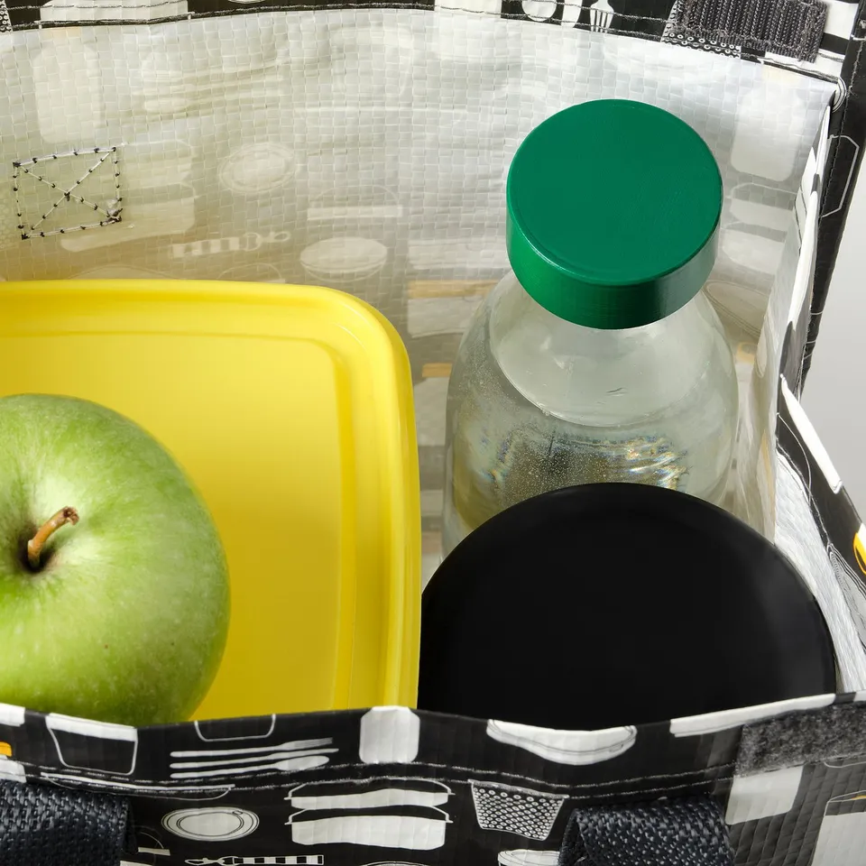 A green apple and a plastic water bottle with a green cap sit next to a yellow container in a mesh compartment, perfect for holding drinks on the go.
