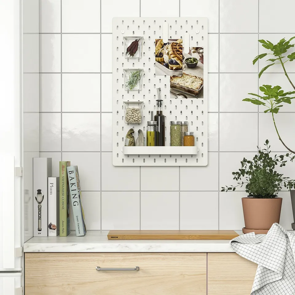 Kitchen pegboard organiser with spice jars, herbs, and photos.