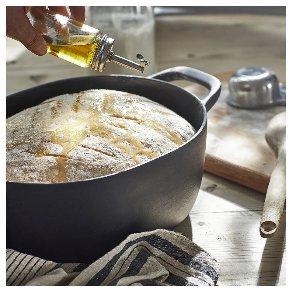 Pouring oil into dough on wood.