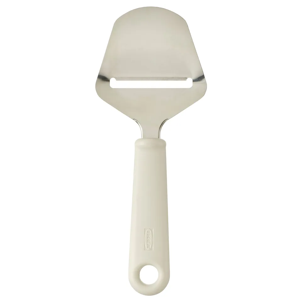 An UPPFYLLD cheese knife with a white handle and stainless steel blade. Its shape is sleek and triangular, designed for slicing cheese easily.