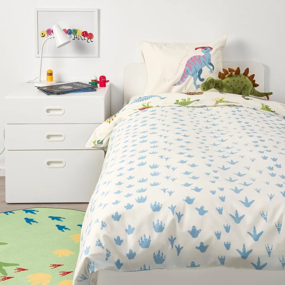 Kids dinosaur bed with JÄTTELIK duvet, pillows, drawers, and rug.