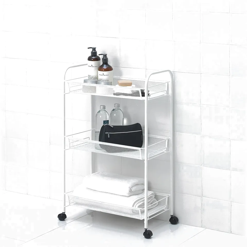 White metal bathroom trolley with multiple shelves. Holds toiletries, bottles, towels, and a black bag. Four wheels for easy movement.