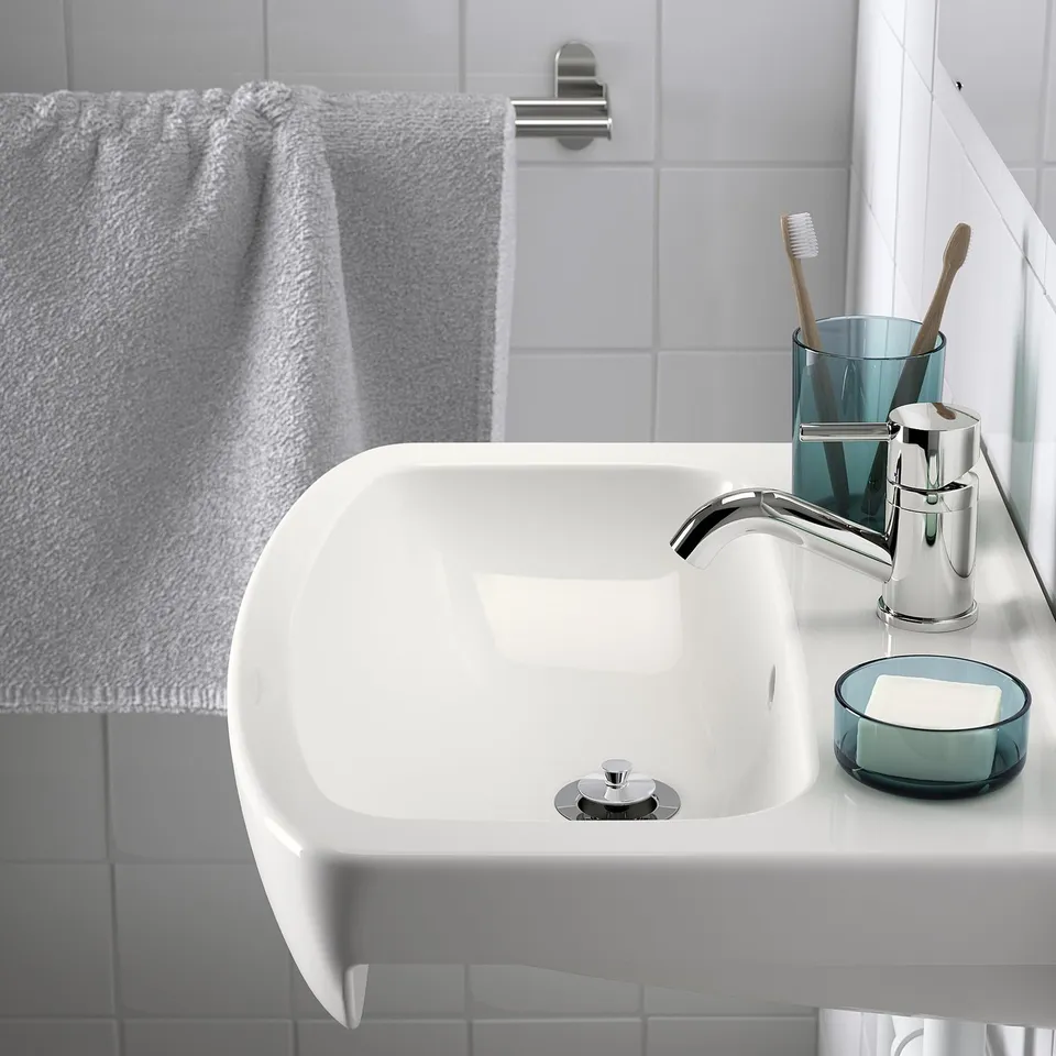 Modern bathroom sink, chrome tap, toothbrush holder with soap dish on counter.