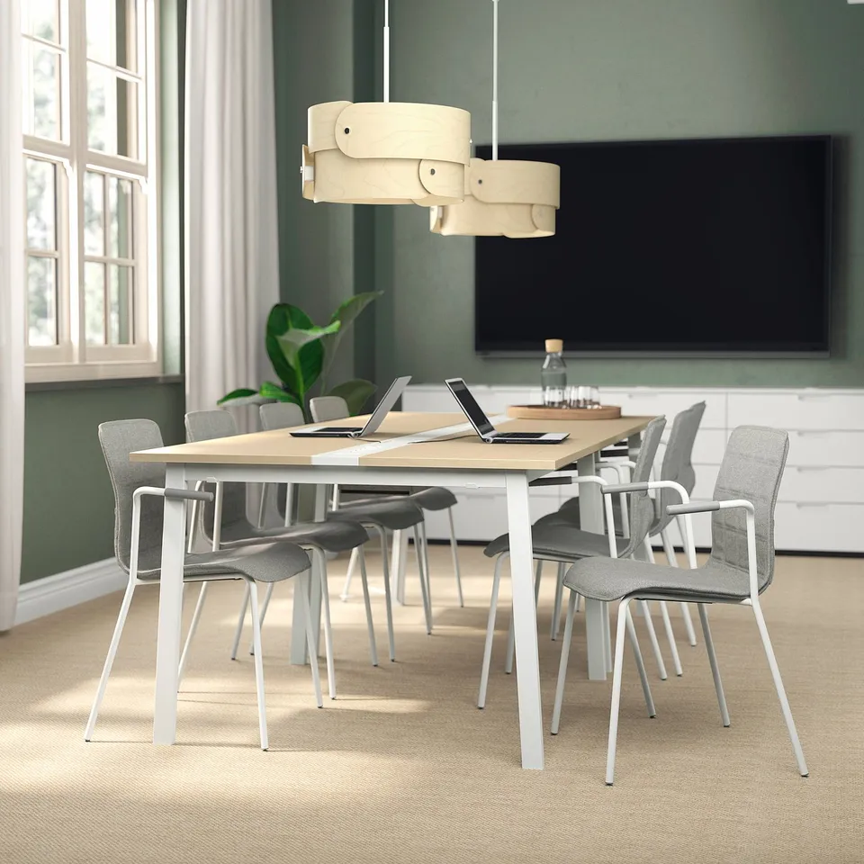 Modern MITTZON conference table with grey chairs, large screen, and unique pendant light. Light wood top, white legs, and green walls.