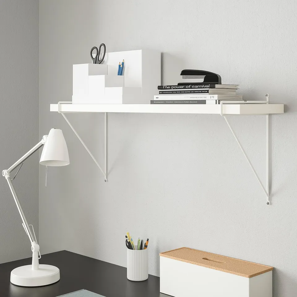 White wall shelf holds books, office items. Modern, minimalist design with steel brackets.