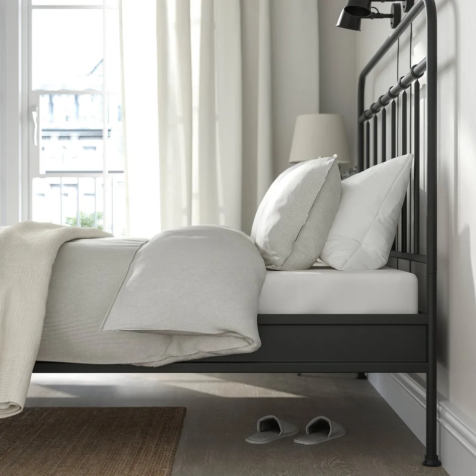 Modern bed with curved headboard, slatted design, and soft lighting for reading.