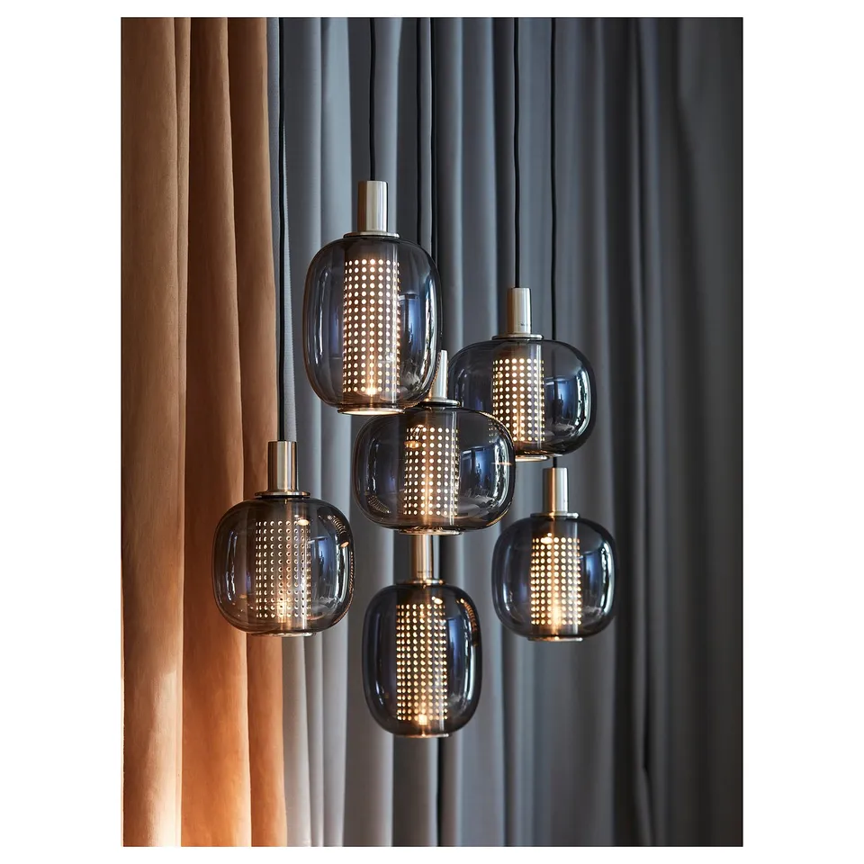 HÖGVIND pendant lamps with smoked glass and metal shades, warm light, dark curtain backdrop