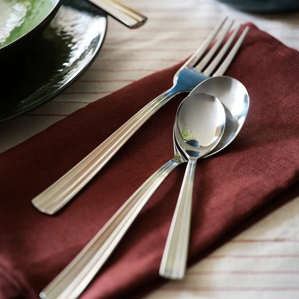SJUGÄLSHAJ cutlery on burgundy napkin. Stainless steel, sleek design.
