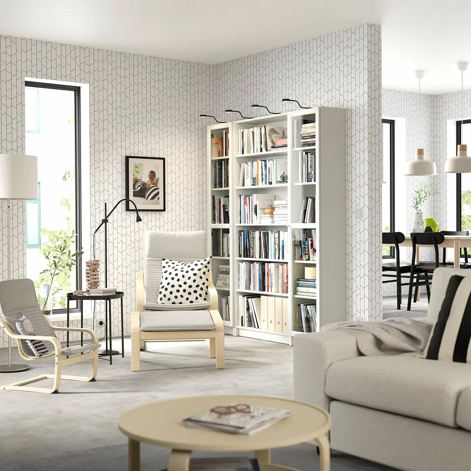 Modern living room with white BILLY bookcases, beige & black furniture, light grey wallpaper.
