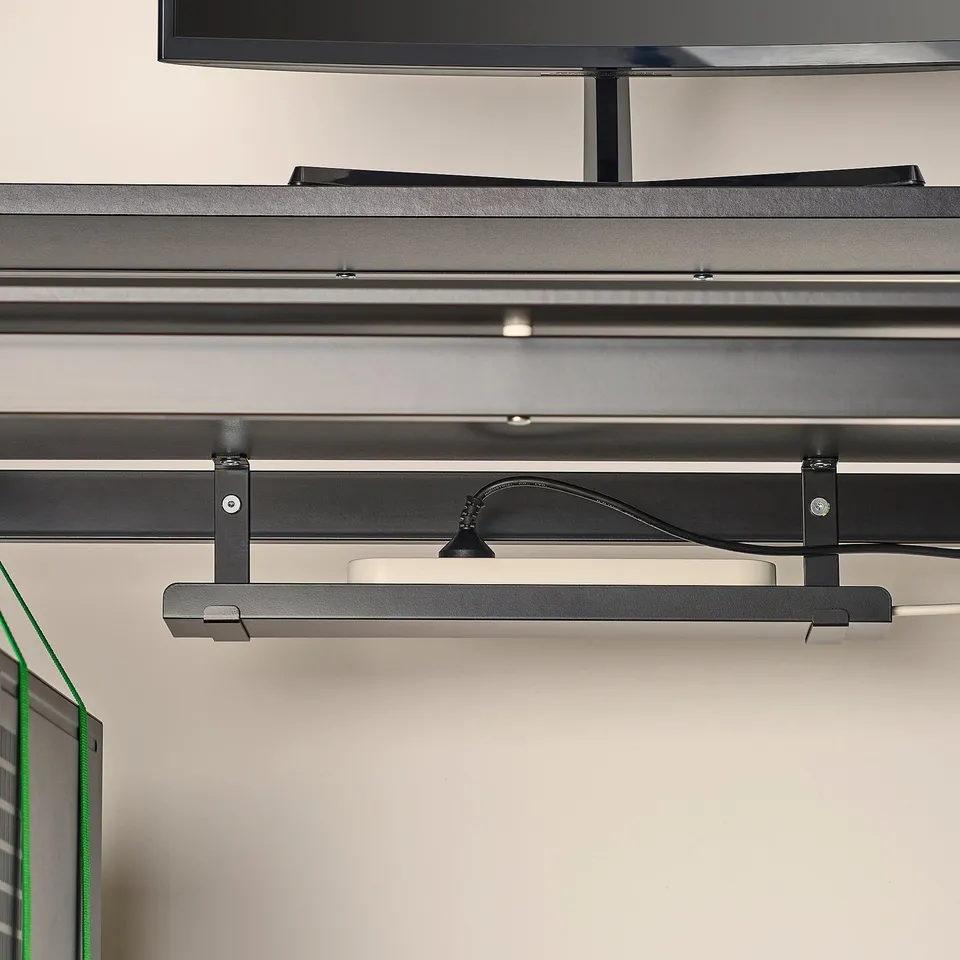 Under-monitor shelf on a gaming desk with height adjustment and cable management.