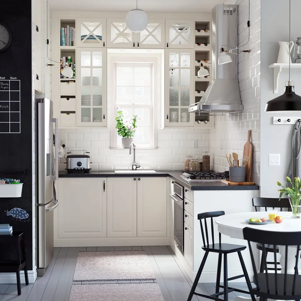 Modern kitchen with white cabinets, black chairs, stainless appliances, and a junior chair for a child.