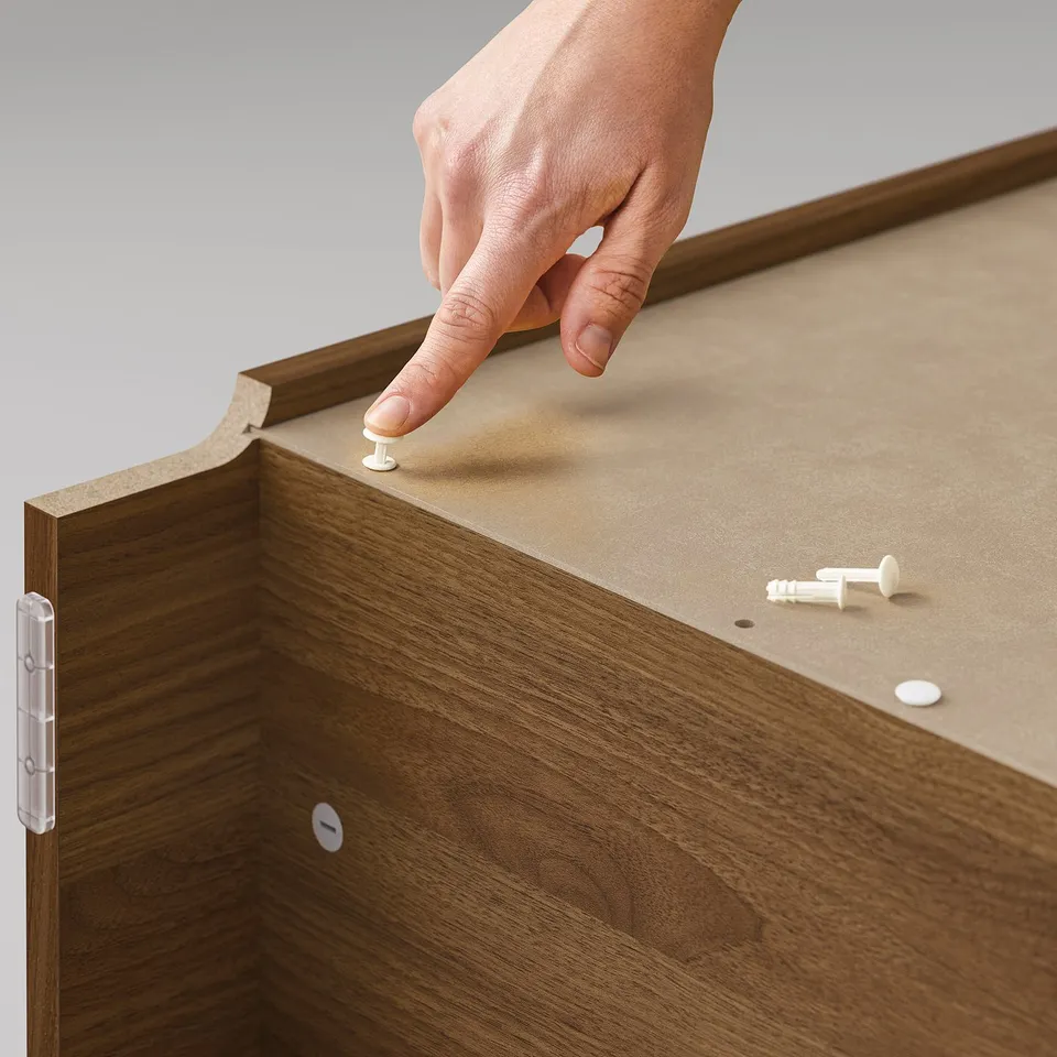 Hand assembling BILLY bookcase, brown, wood grain texture, using plastic snap fittings.