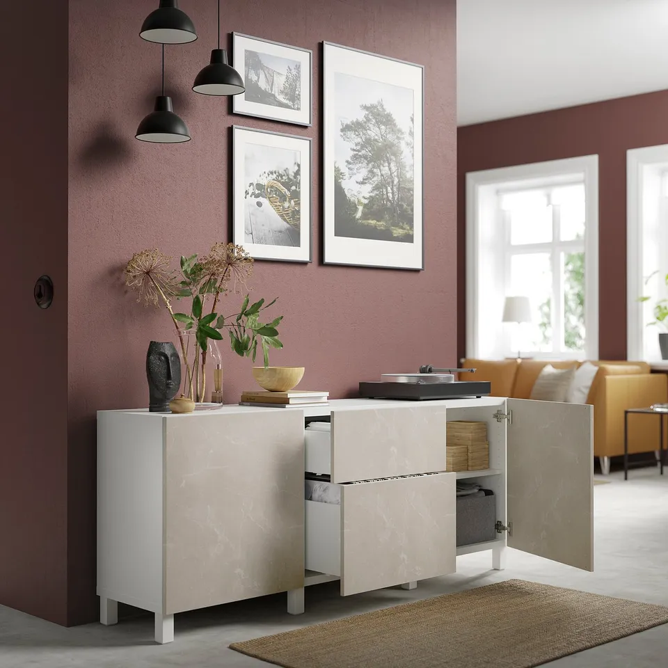 Modern living room with white marble-like sideboard featuring open doors, adjustable shelves, and drawers. Natural decor and adjustable hinges.