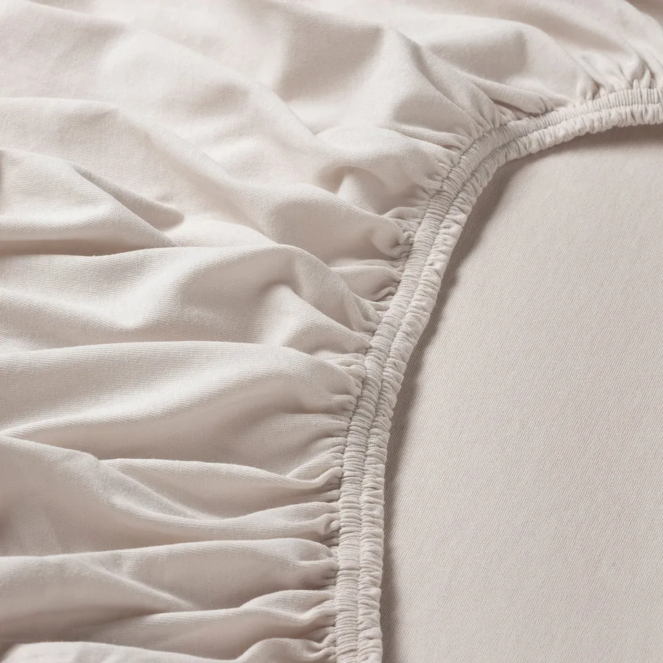 Close-up of soft, light-colored fabric with gathered, elastic edge, showing quality texture and stitching.