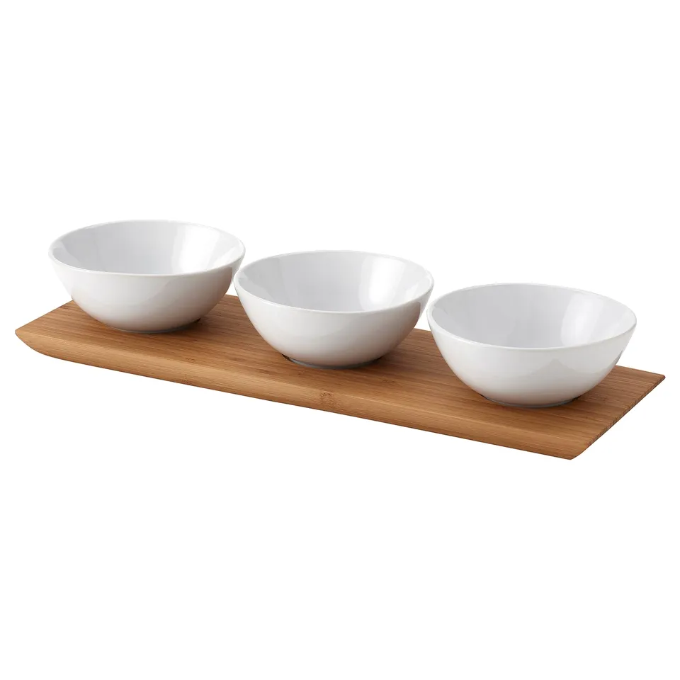 TYNGDLÖS tray set: three white ceramic bowls on a bamboo base. Perfect for serving snacks or shared dishes. Simple, elegant design.