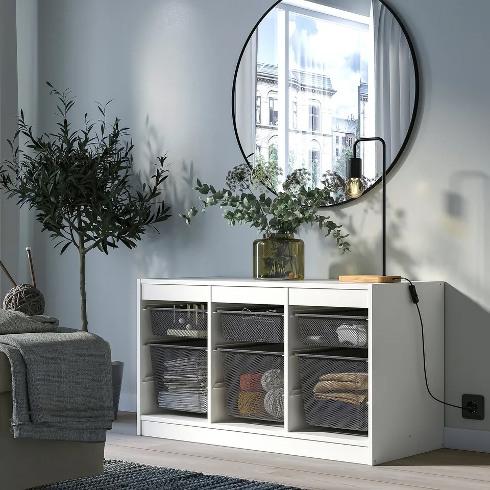 Modern living space with a white TROFAST storage unit, round mirror, and olive tree.