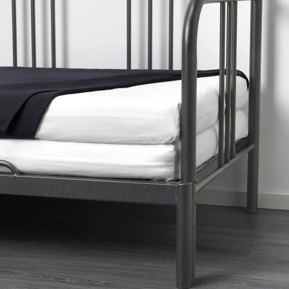 A modern black metal daybed with two white mattresses stacked, transforming it into a sofa.
