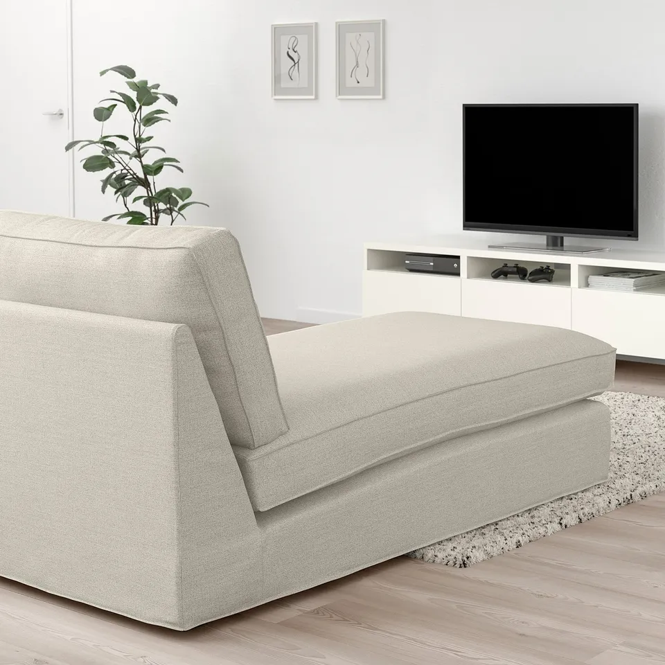 A modern living room featuring a KIVIK chaise longue in beige next to a tv, with ample cushions, a plant, and minimalist decor.
