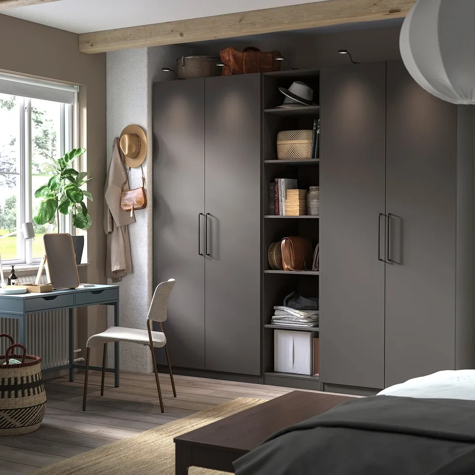 Modern bedroom with grey PAX wardrobe, desk, and plant.