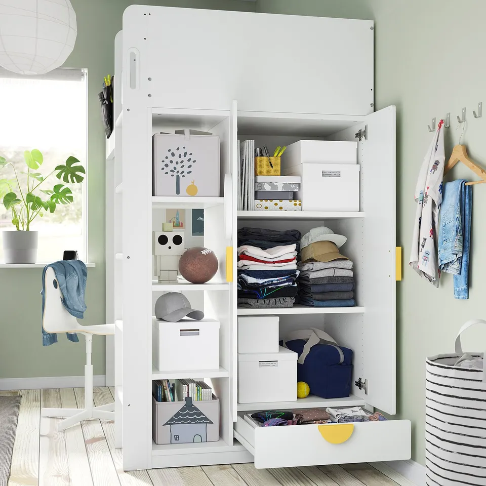 Ikea SMÅSTAD loft bed open, showing organized clothes, books, and storage. Desk below with drawer open.