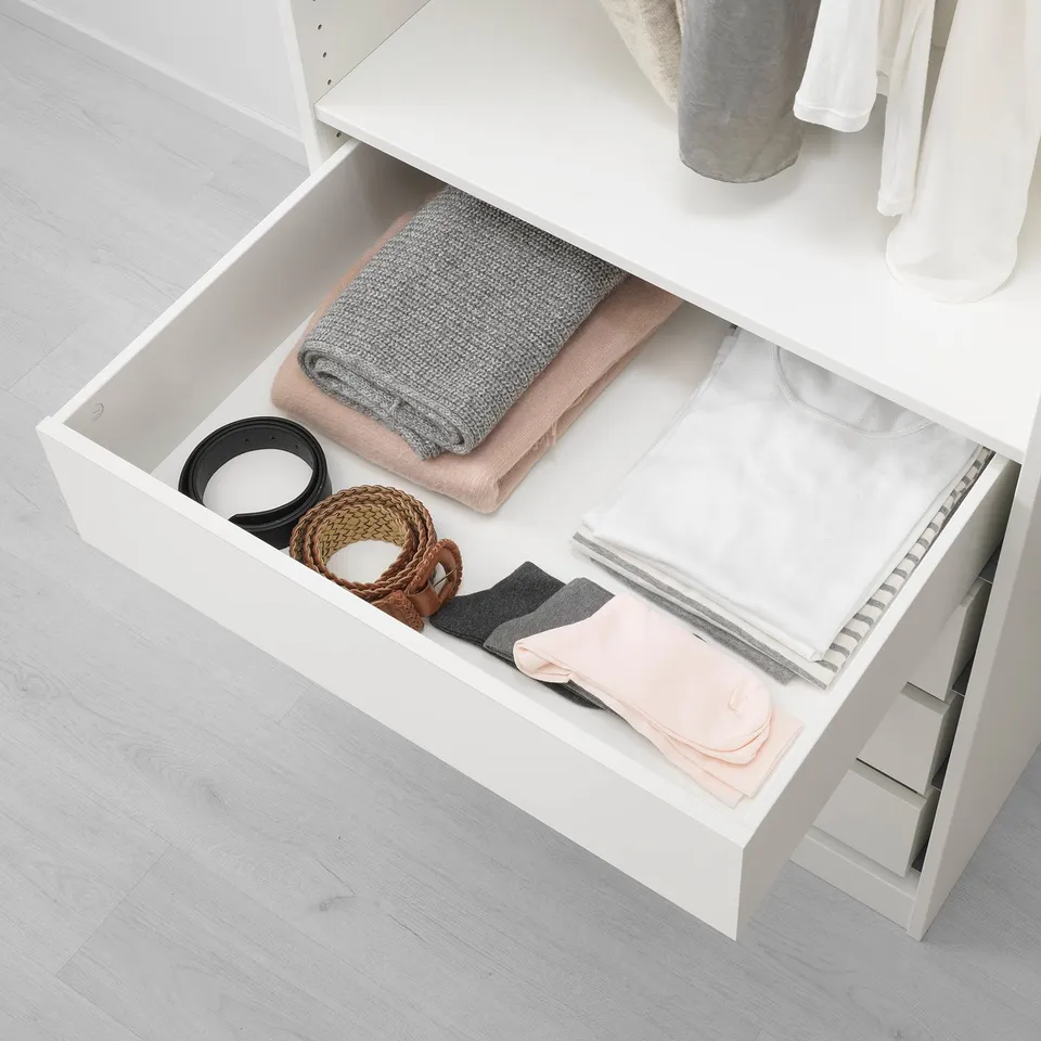 Open wardrobe drawer showing organised clothes: folded blankets, socks, and accessories.