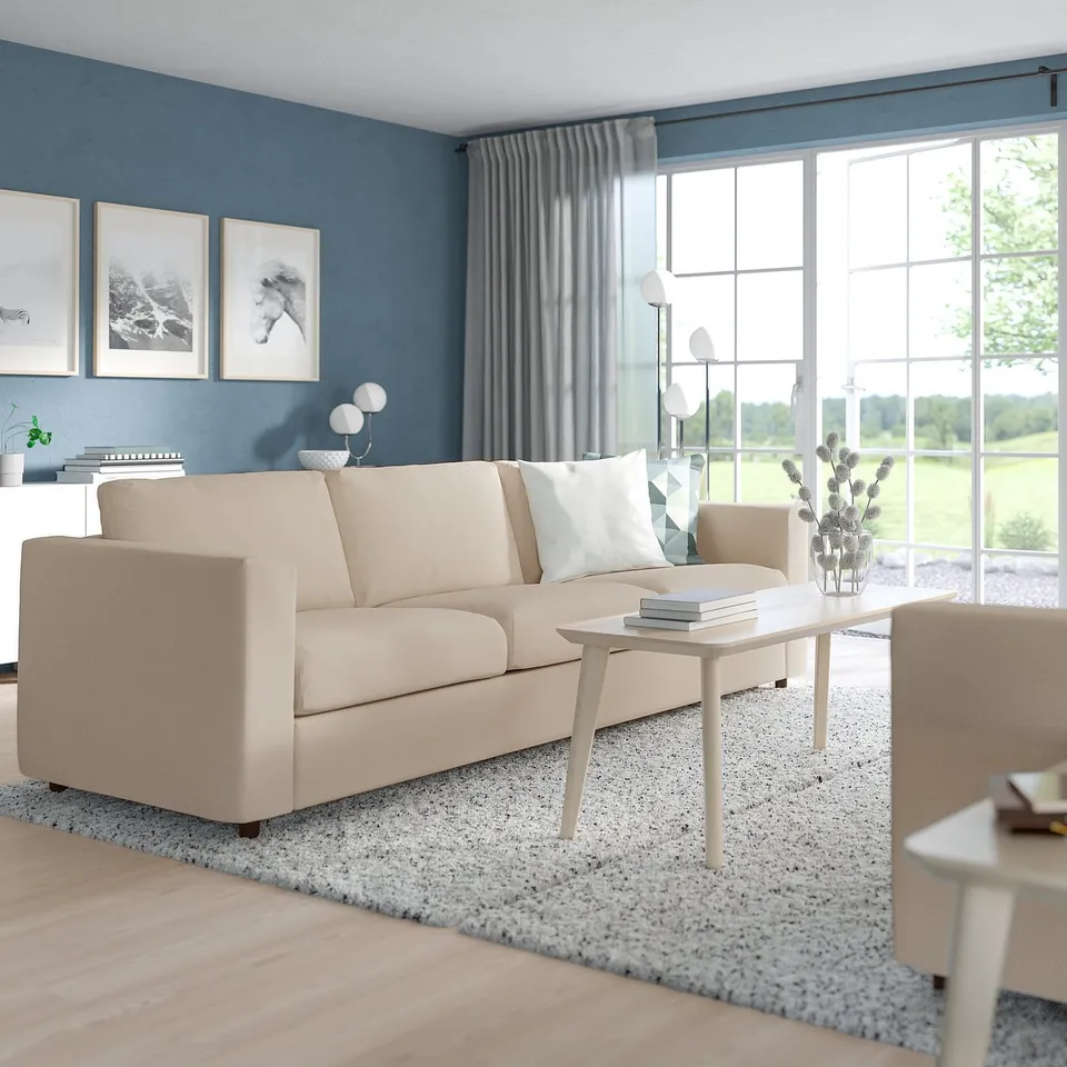Modern living room with VIMLE beige sofa, it matches the neutral decor, including speckled rug. Large windows bring nature inside.