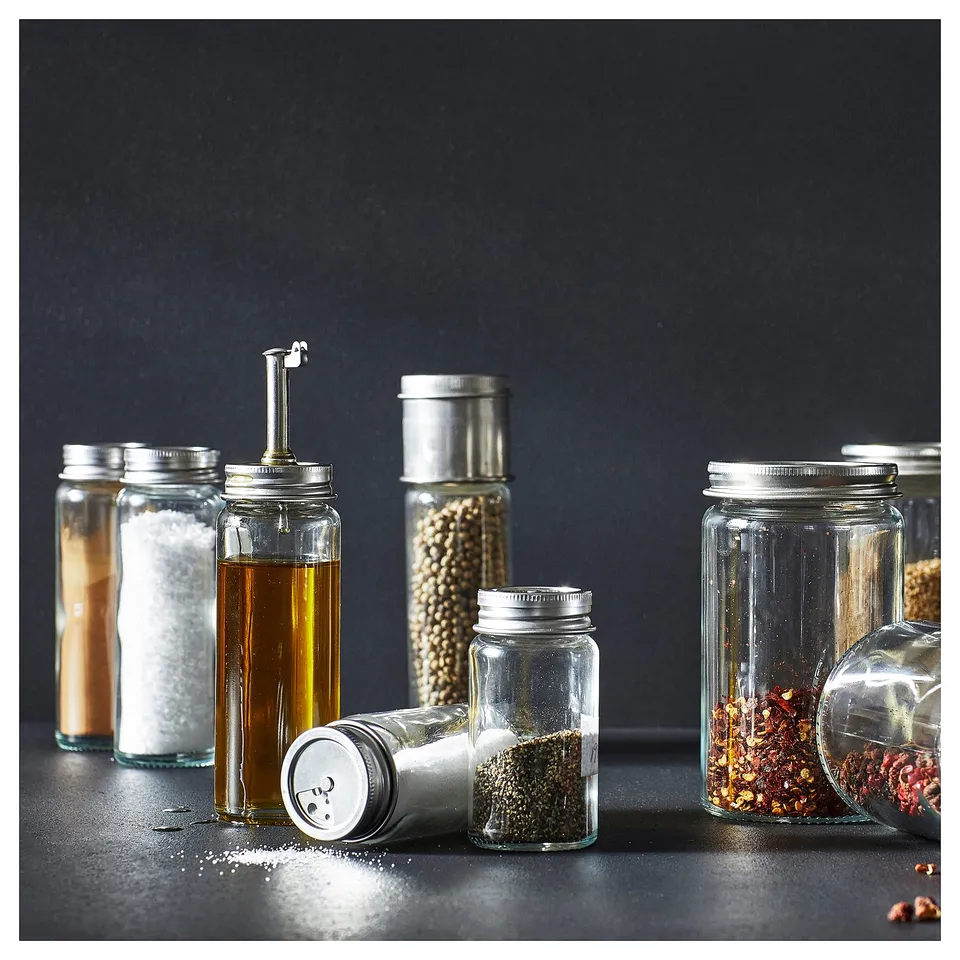 Assorted CITRONHAJ glass spice jars with metal lids on black countertop, containing various spices and oils.