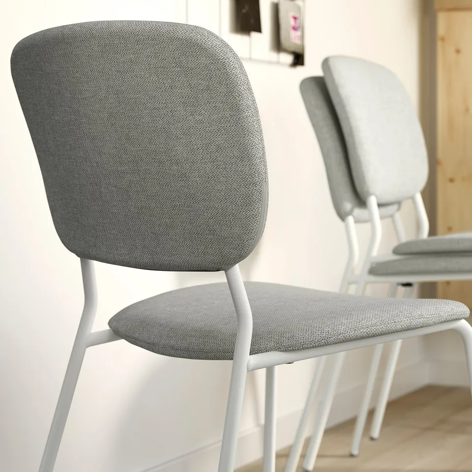 Modern grey upholstered chairs with white metal legs, ideal for dining, neatly arranged in a minimalist setting.