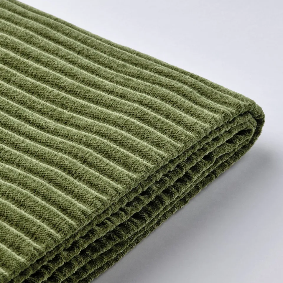 Close-up of textured green fabric, likely a sofa cover. Exhibits ribbed, corduroy-like pattern.