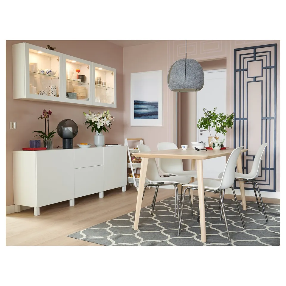Community dining area with bold pink walls, modern white furniture, geometric patterns, and hanging lamps.