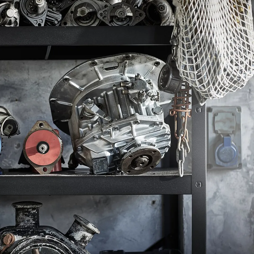 Black metal shelf holding large industrial gears and motors, including blue and red circular parts. Mechanics storage solution.