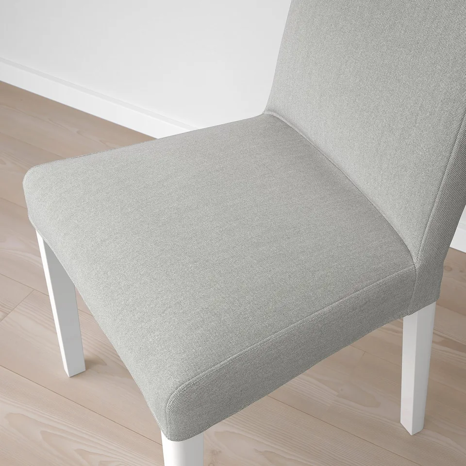 Modern chair with sleek design: curved back, light fabric, wooden floor.