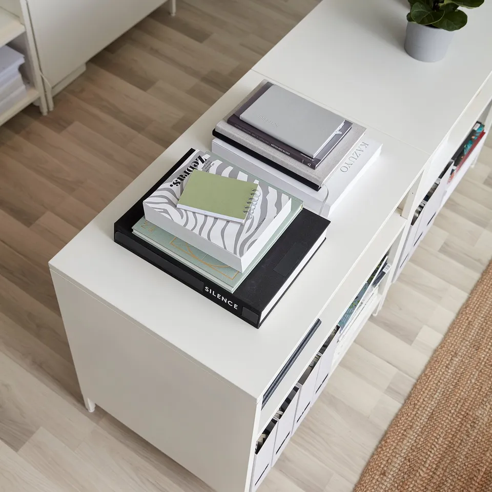 A TROTTEN double-sided cabinet with adjustable shelves, housing books and a plant, dividing a room.
