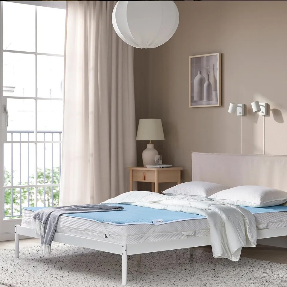 Bedroom with REXBEGONIA mattress protector, large bed, beige wall, window, and balcony.
