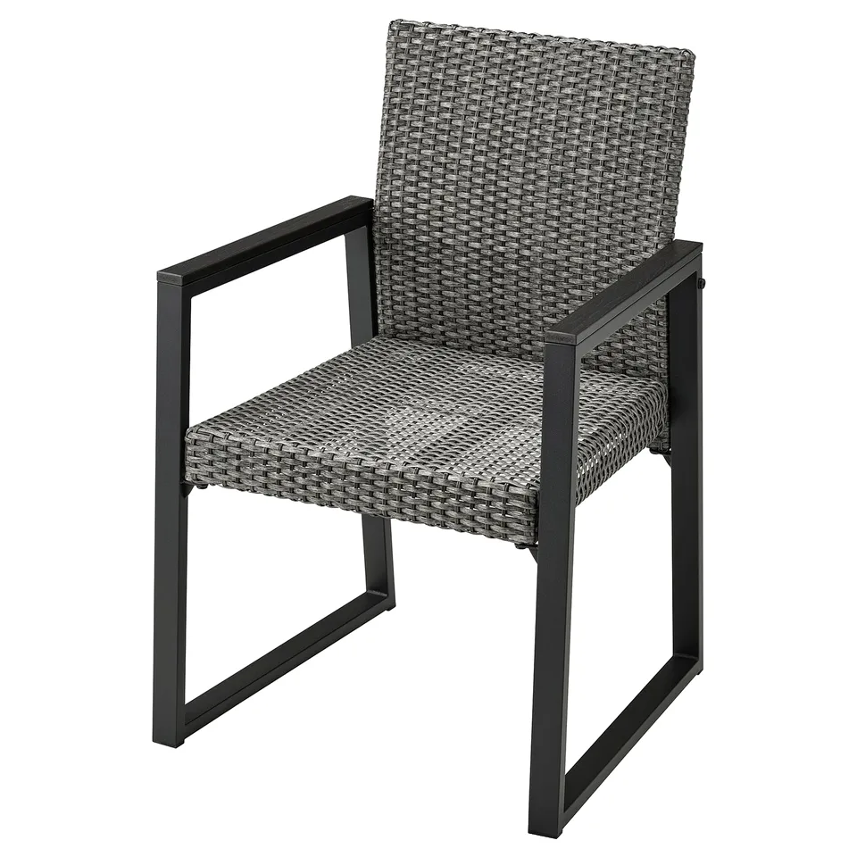 Single VÄRMANSÖ wicker outdoor chair in grey, featuring curved back and armrests, supported by black metal frame.