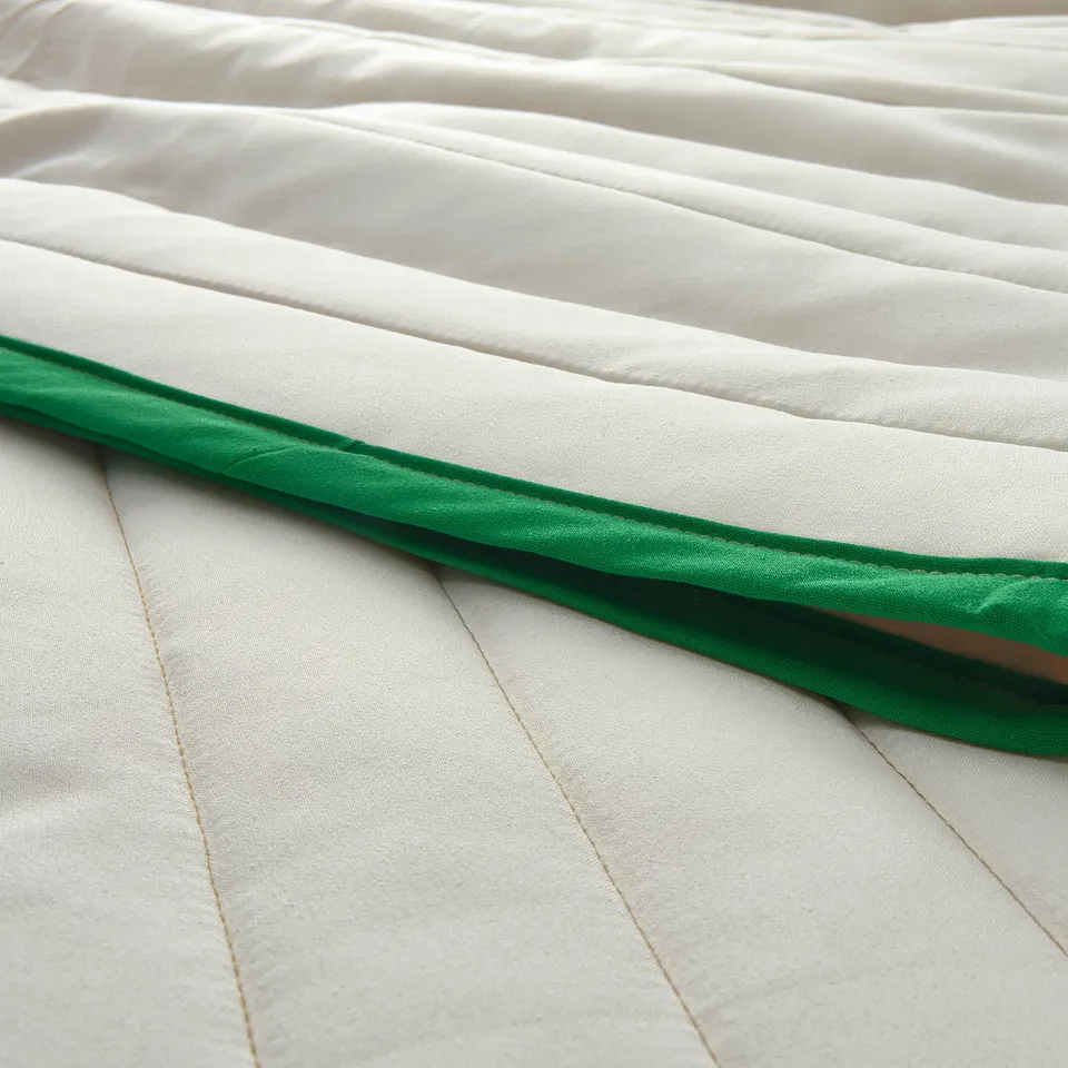 Soft, white bedspread with striped design and green edge, showcasing quality fabric.