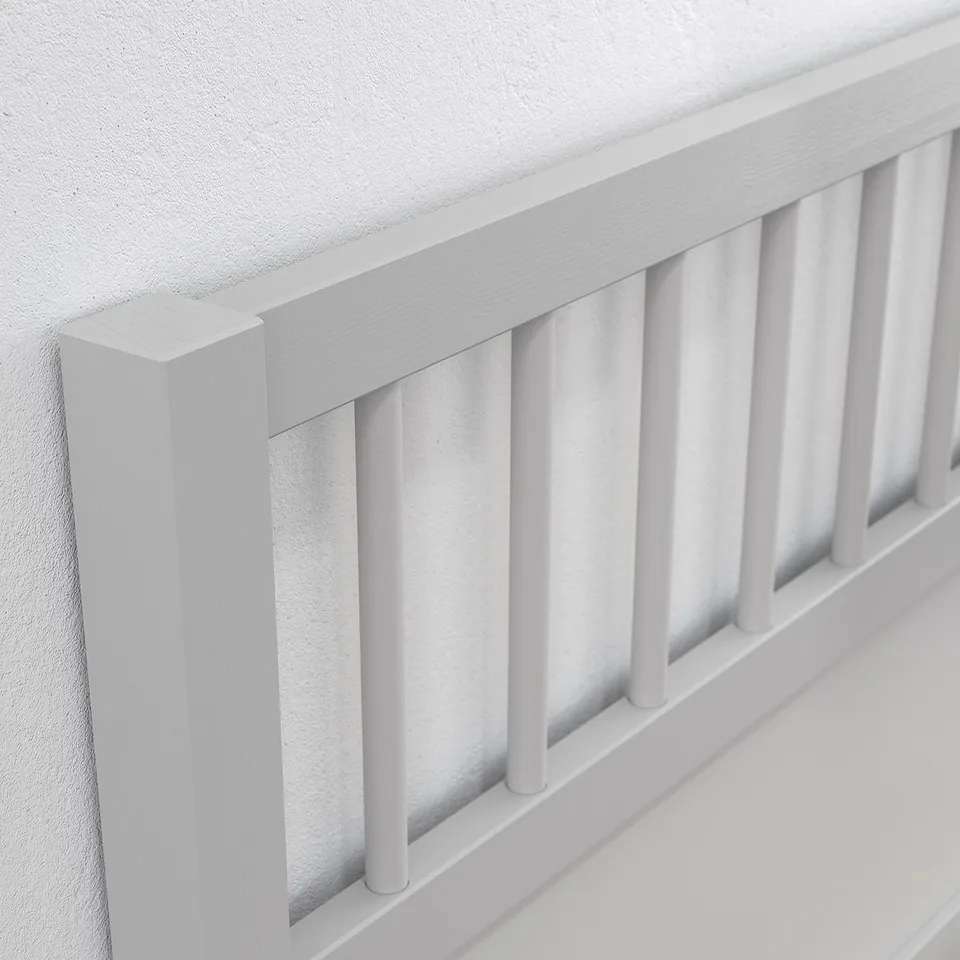Close-up of sleek, modern white wooden bedframe. Sturdy vertical slats and crisp edges show high-quality craftsmanship.