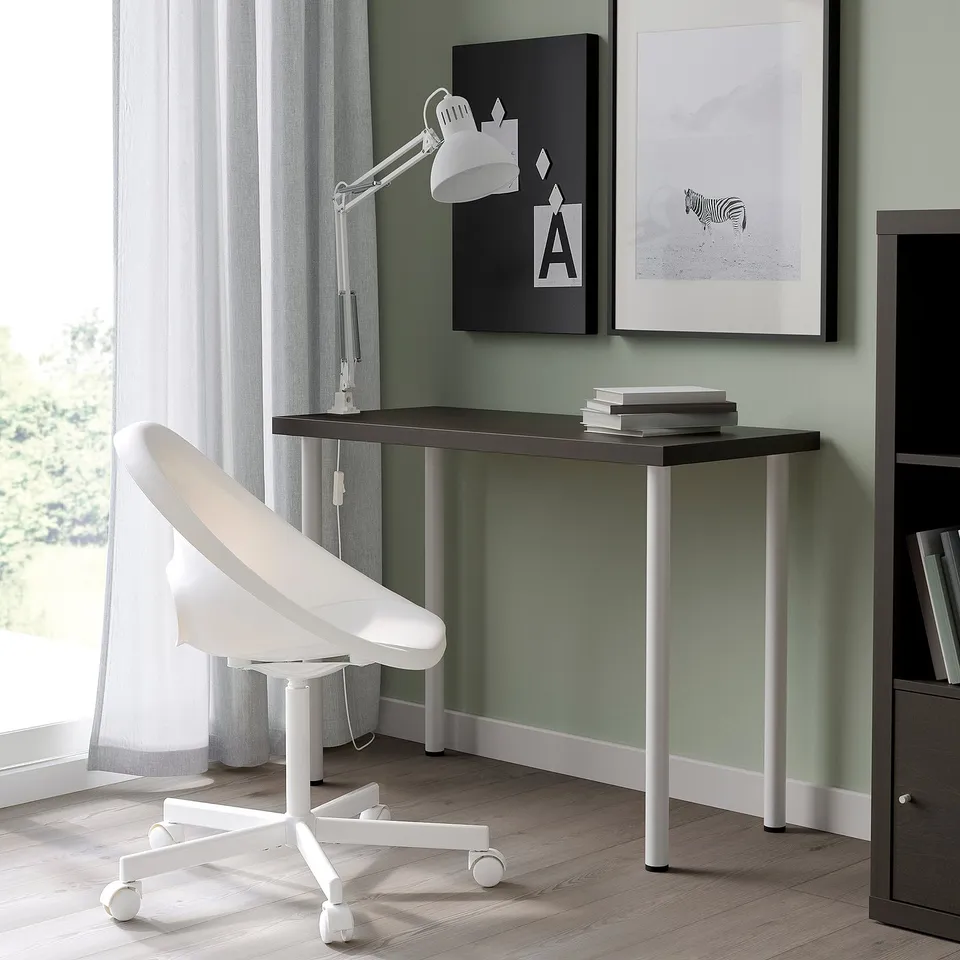 Modern workspace with black desk, white cabinet, ergonomic chair, green art wall, and natural light.