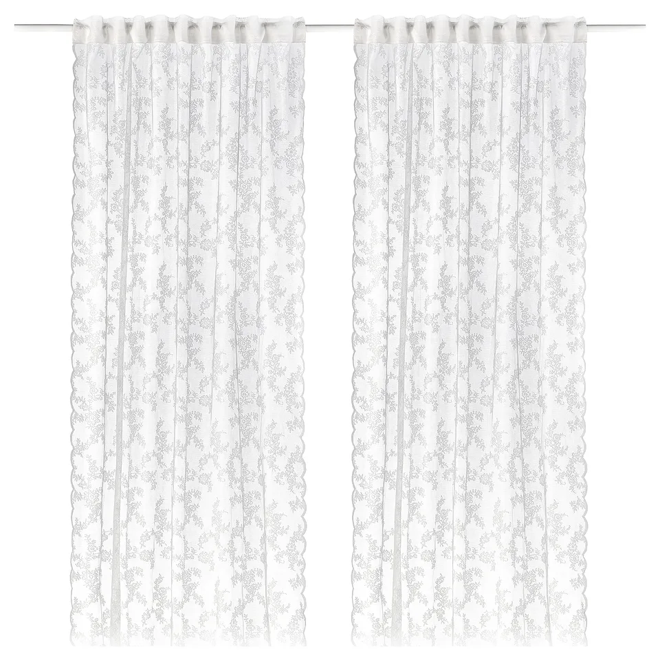 Pair of white lace curtains with floral patterns and scalloped edges.
