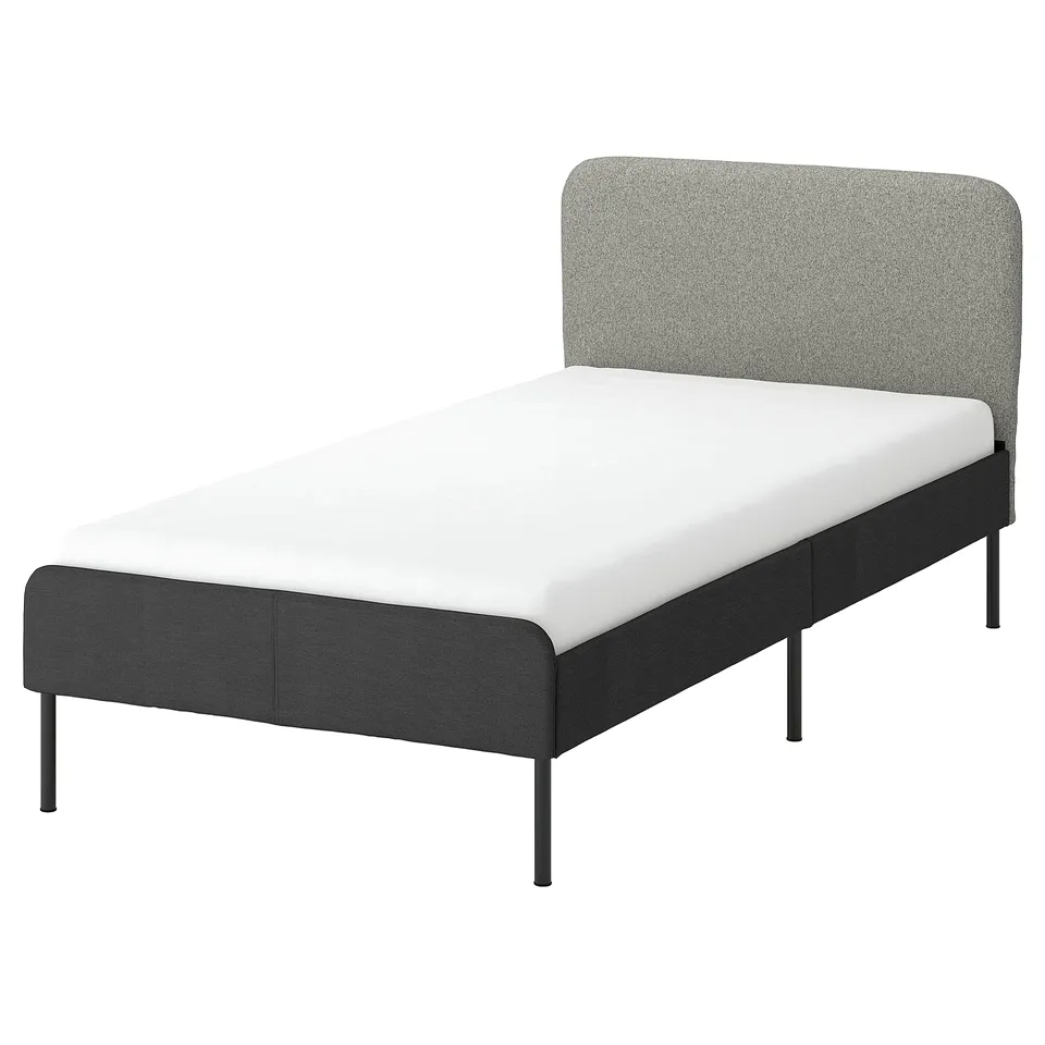A SLATTUM bed frame in dark grey with a padded headboard and a white mattress. The design is modern, minimalist, and comfortable.