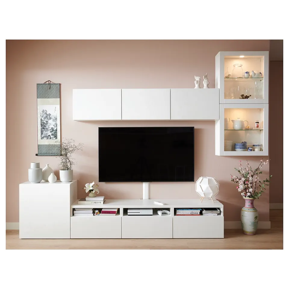 Modern living room setup with white BESTÅ tv storage combination. Includes tv, shelves, and drawers. Decorated with vases and books.