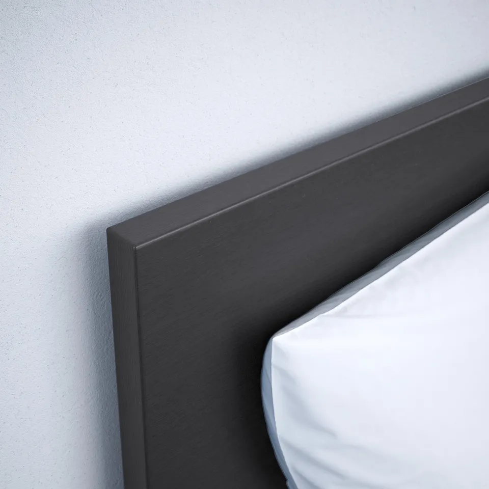 Close-up of a dark grey bed frames corner, showing smooth edges and a crisp finish against a light wall.