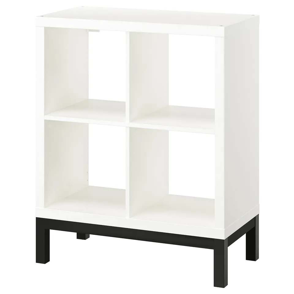 KALLAX white cube shelf, four square sections, black metal base, modern minimal design.