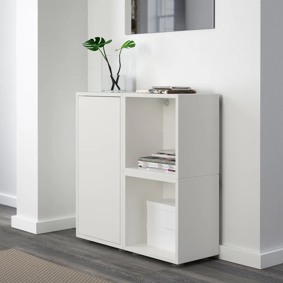 White EKET storage unit with open and closed sections. Top holds magazines and a plant.