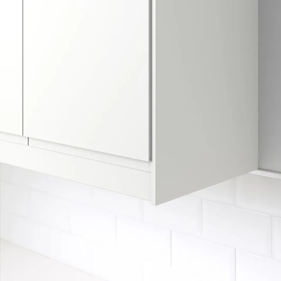 White kitchen cabinet trim, hiding cables, mounted on tiled wall.